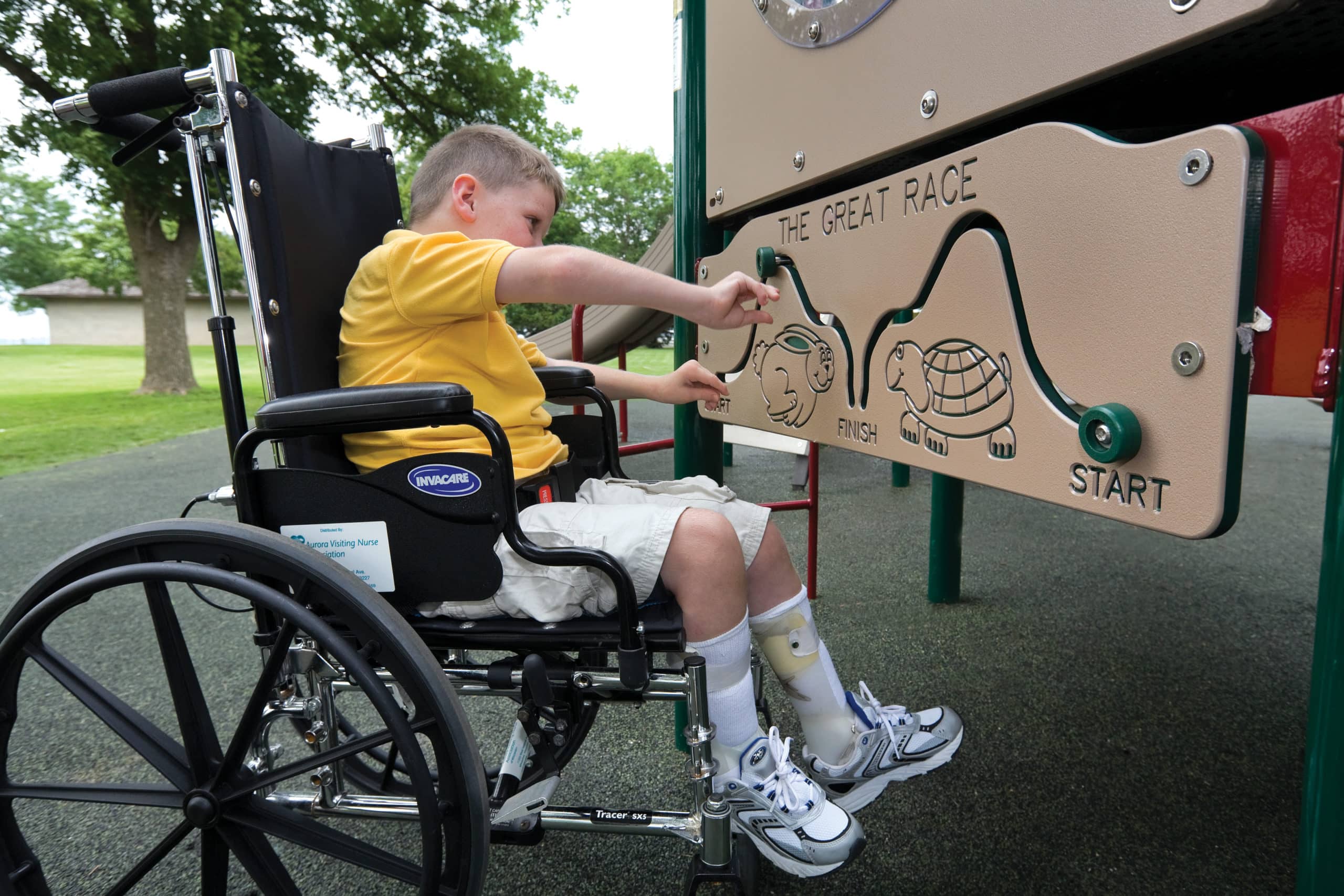 Young boy in wheelchair playing with The Great Race playground game panel